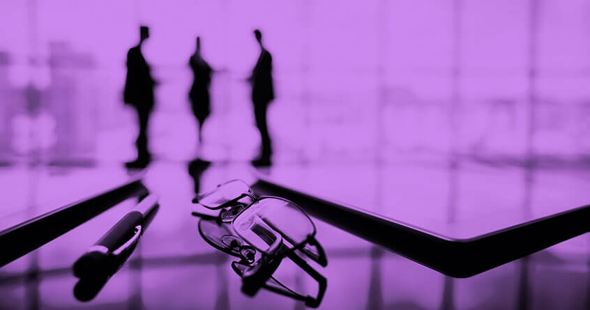 משפקיים ועט על שולחן משרדי ומאחור 3 דמויות מתדיינות