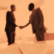 דמויות לוחצות ידיים מעל לשלוחן במשרד